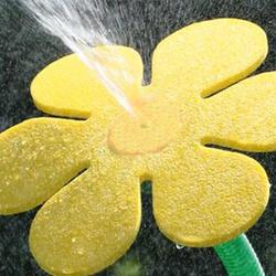 Aspersor galben în formă de floare stropește apa în sus.