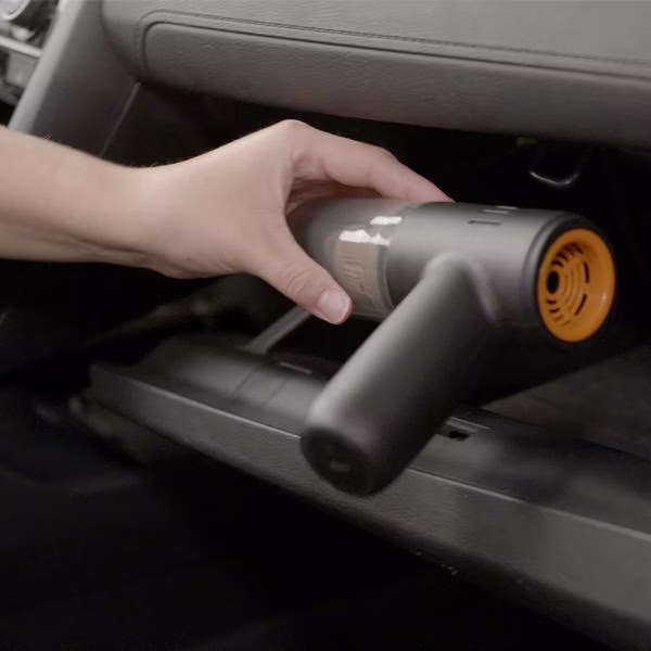 Un aspirator de mână este folosit în mașină sub torpedou – ideal pentru zonele greu accesibile din interior.